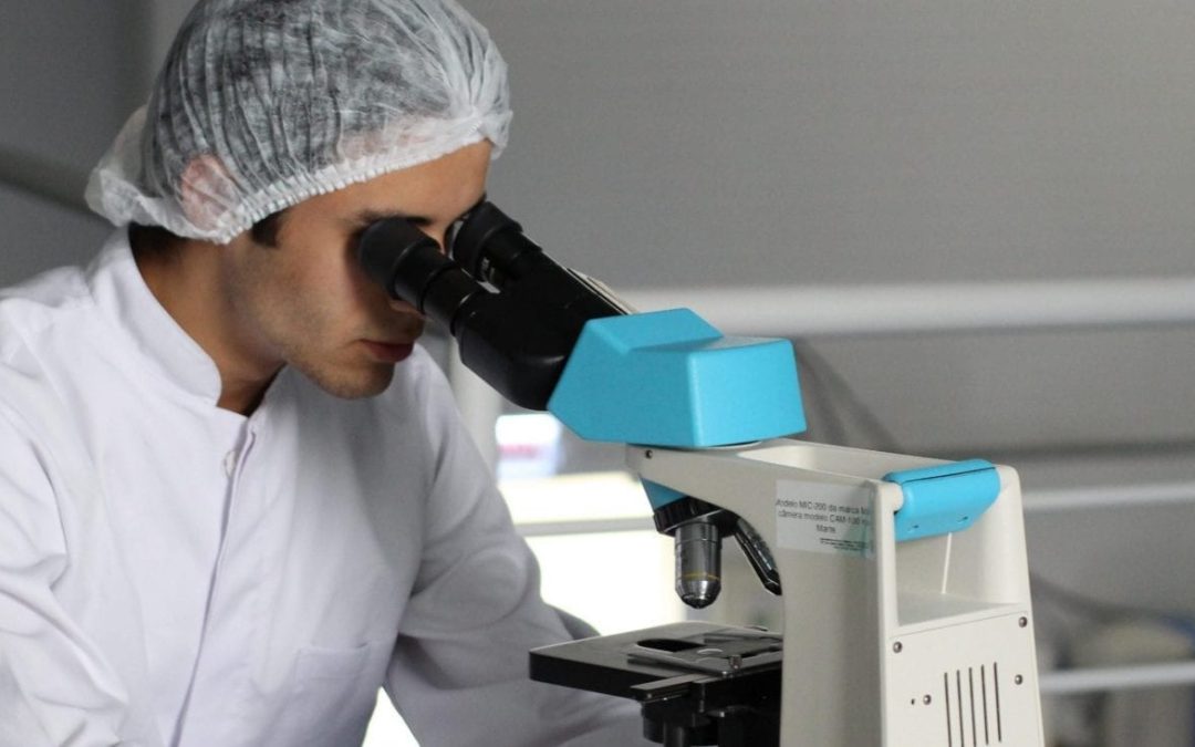 scientist looking through microscope